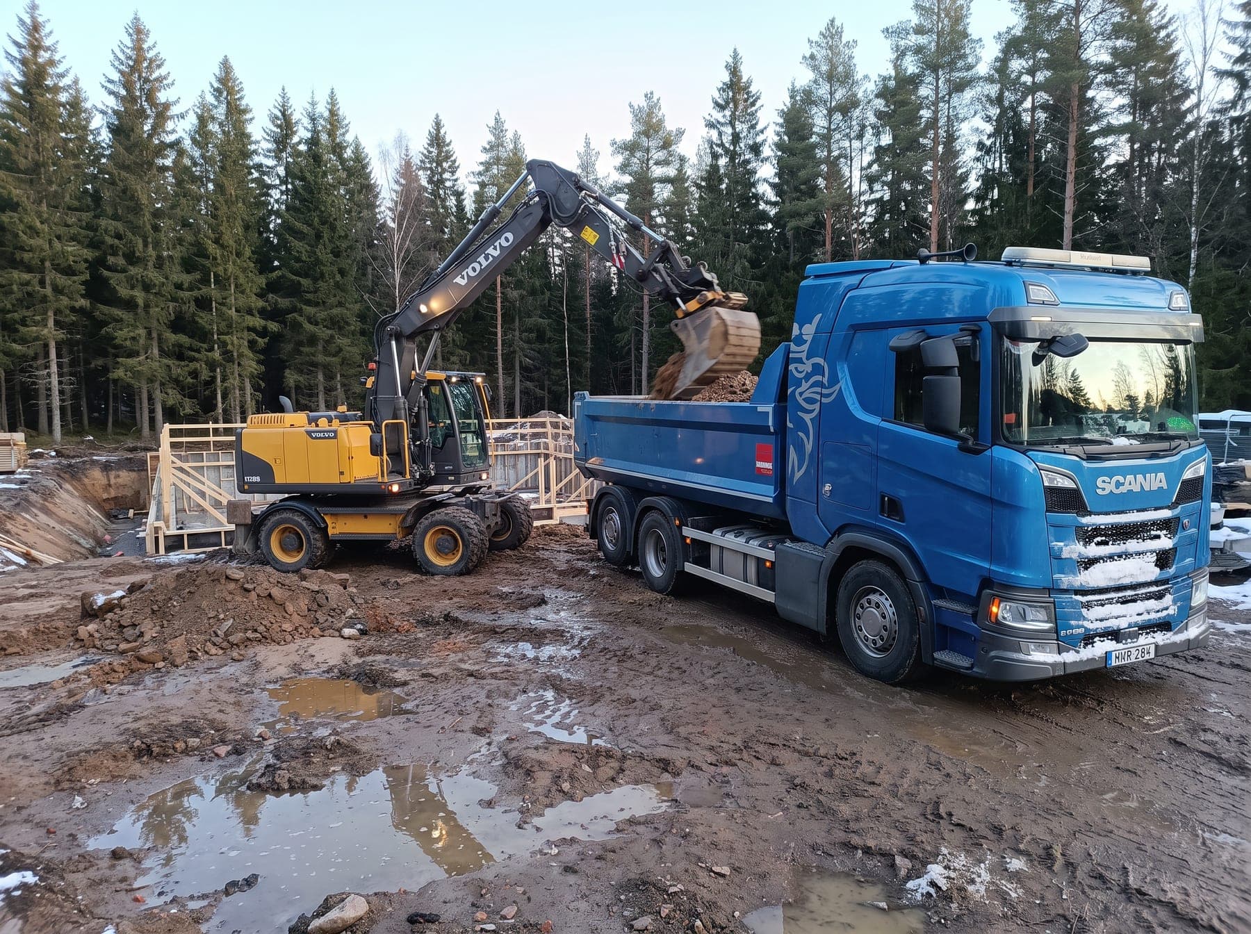 Hjulgrävare lastar schaktmassor i tippbilen vid en husgrund